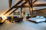 Experience luxurious loft living in this stunning bedroom suite, featuring dramatic exposed wooden beams and a vaulted ceiling.