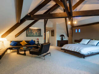 Experience luxurious loft living in this stunning bedroom suite, featuring dramatic exposed wooden beams and a vaulted ceiling.