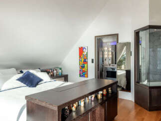 Discover this unique bedroom featuring a comfortable bed with crisp white linens and a striking blue accent pillow.