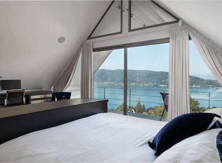 Experience breathtaking lake views from this stunning bedroom, featuring a spacious desk area perfect for a home office.