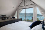Experience breathtaking lake views from this stunning bedroom, featuring a spacious desk area perfect for a home office.