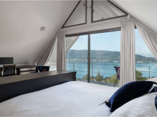 Experience breathtaking lake views from this stunning bedroom, featuring a spacious desk area perfect for a home office.