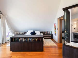 This spacious bedroom features a built-in dark wood bookcase that spans the width of the bed, offering ample storage for books and decor.