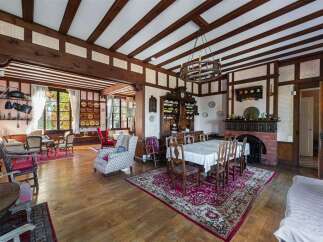 Step into a charming dining and living area featuring exposed wooden beams and a classic fireplace.