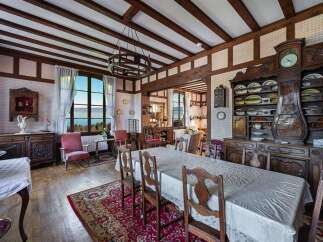 Experience elegant dining in this charming room featuring a large wooden table draped in a white tablecloth, perfect for hosting gatherings.