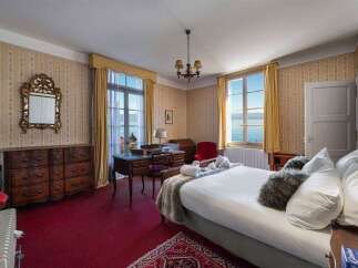 Experience breathtaking lake views from this charming bedroom, featuring elegant wallpaper and a classic wooden dresser.