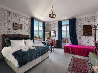 Experience breathtaking lake views from this charming bedroom, featuring elegant floral wallpaper and large windows that flood the space with natural light.