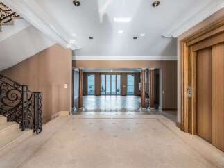 Step into luxury with this grand foyer featuring a sweeping staircase with ornate iron railings and elegant marble flooring.