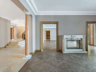 Step into an elegant foyer featuring a grand marble staircase and a decorative column, leading to a spacious living area.
