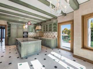 Step into this charming kitchen featuring custom sage green cabinetry and a large marble-topped island, perfect for culinary creations.
