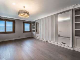 Experience luxury living in this spacious room featuring elegant floor-to-ceiling mirrored wardrobes and built-in shelving.