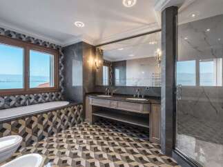 Experience luxury in this stunning bathroom featuring a deep soaking tub with a picturesque view of the water and mountains.