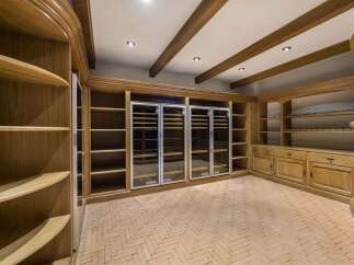 Discover this exquisite wine cellar featuring custom oak cabinetry and built-in wine refrigerators, perfect for the discerning collector.