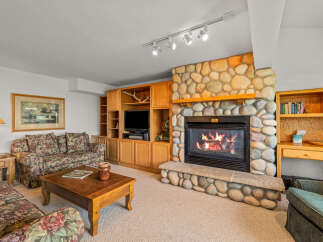 Cozy up by the stunning stone fireplace in this inviting living room, perfect for relaxing evenings.