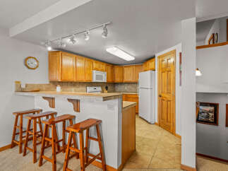 This charming kitchen features warm oak cabinetry and a convenient breakfast bar with four wooden stools, perfect for casual dining.