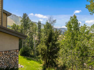 Experience breathtaking mountain views from this stunning property, featuring a unique stone and wood exterior.