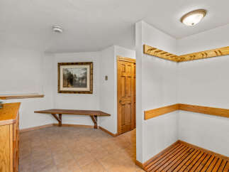 This entryway features a wooden bench and a wooden cabinet, perfect for storing shoes and outerwear.