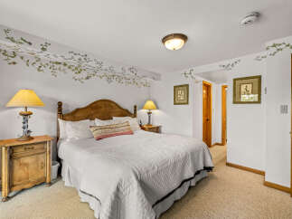 Step into this charming bedroom featuring a cozy queen-size bed adorned with a decorative throw pillow and crisp white linens.