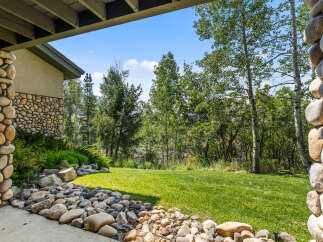 Experience the beauty of nature from this stunning property, featuring a charming stone exterior and a lush green lawn perfect for outdoor activities.