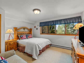 Experience cozy comfort in this charming bedroom, featuring a rustic wooden headboard and patriotic-themed pillows.
