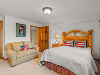 This charming bedroom features a cozy queen-size bed with patriotic-themed pillows and a matching bed skirt.