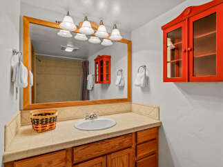 This charming bathroom features a spacious vanity with a tiled countertop and a large wooden-framed mirror.