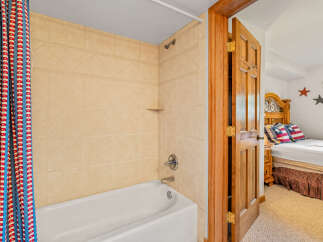 This charming bathroom features a classic tiled shower and tub combination, complemented by a vibrant, patriotic shower curtain.
