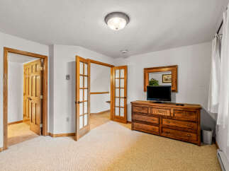 Discover comfort and style in this inviting room, featuring a spacious wooden dresser topped with a television and a decorative mirror.