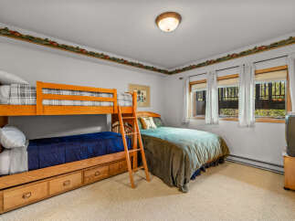 This charming bedroom features a space-saving bunk bed with built-in drawers, perfect for accommodating guests or children.
