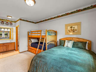 This charming bedroom offers versatile sleeping arrangements with a full-size bed and a bunk bed, perfect for families or groups.