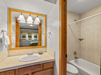 This charming bathroom features a spacious vanity with a tiled countertop and a wooden cabinet, perfect for storage.