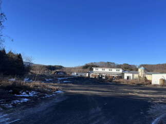 Discover this expansive property featuring multiple buildings, including a main structure with upper and lower levels, and additional outbuildings.