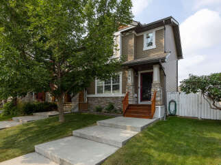 Charming townhouse with a welcoming front porch and natural stone accents.