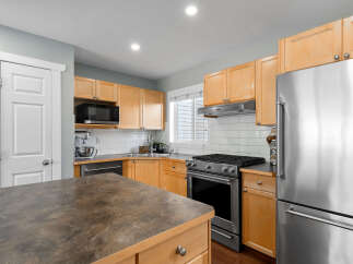 Discover this beautifully updated kitchen featuring sleek stainless steel appliances, including a modern gas range and a spacious refrigerator.