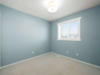 This empty room features calming blue walls and a neutral carpet, creating a serene atmosphere.