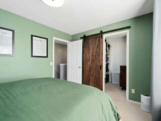 This bedroom features a calming sage green accent wall, complemented by two framed art pieces.