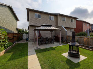 Enjoy outdoor living in this spacious backyard featuring a covered patio with a dining set, perfect for al fresco meals.
