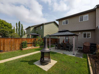 Enjoy outdoor living in this spacious backyard featuring a covered patio with a dining set, perfect for al fresco meals.
