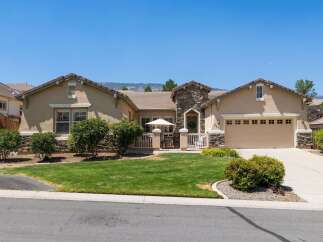 This charming single-story home features a welcoming stone-accented entryway leading to a spacious living area.
