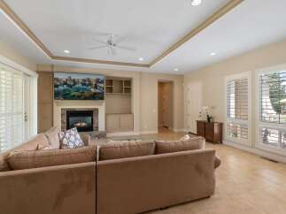 This spacious living room features a large sectional sofa perfect for family gatherings, centered around a cozy fireplace with a mounted television above.