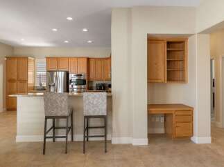 This spacious kitchen features beautiful light wood cabinetry and a large stainless steel refrigerator.