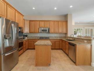 This spacious kitchen boasts beautiful light oak cabinetry and granite countertops, offering ample storage and workspace.