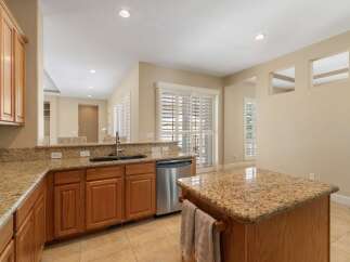 This spacious kitchen boasts beautiful granite countertops and warm wooden cabinetry, offering ample storage and workspace.