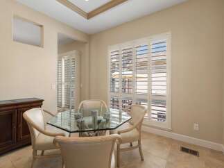 This dining area features a stylish glass-top table with a unique driftwood base, complemented by four elegant upholstered chairs.