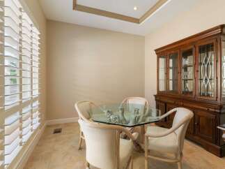 This elegant dining room features a unique glass-top table with a natural wood base, complemented by four upholstered chairs.