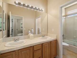 This bathroom features a spacious double vanity with tiled countertops and ample storage below.