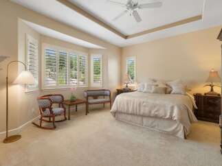 This spacious master bedroom offers a serene retreat with its plush carpeting and elegant tray ceiling.