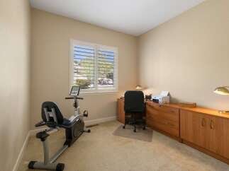 This home office features a recumbent exercise bike for your fitness routine and a dedicated workspace with a desk, chair, and printer.