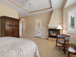 Experience ultimate comfort in this luxurious bedroom featuring a cozy fireplace and a spacious wardrobe.