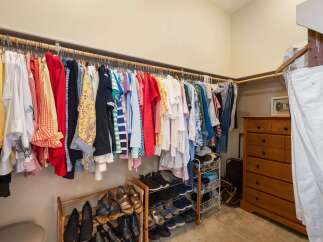 Discover ample storage in this spacious walk-in closet, featuring a well-organized hanging rod for a diverse wardrobe and multiple shoe racks to keep footwear tidy.